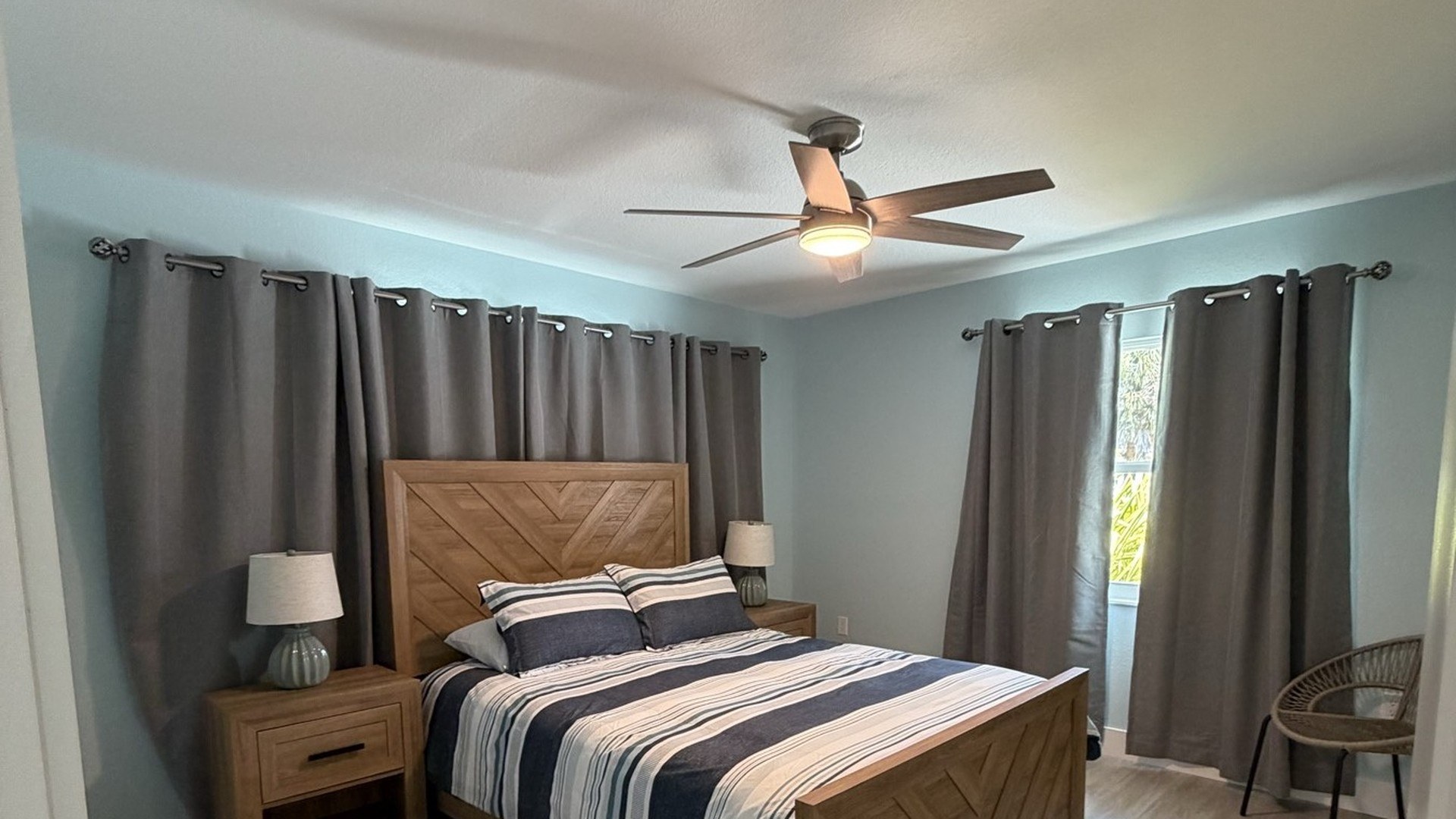 Bedroom with wood chevron headboard, striped bedding, and gray curtains