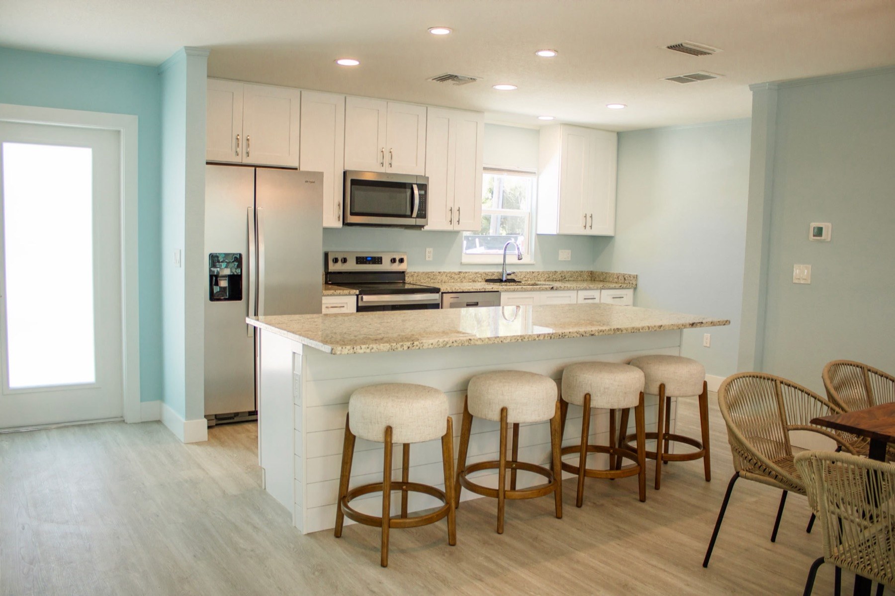 Renovated open kitchen with large island, granite counters, white cabinets, and stainless appliances